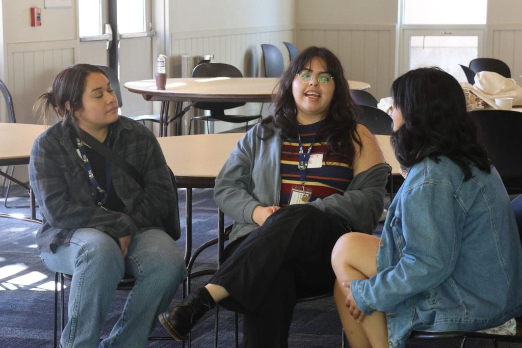 three students in group sitting down having a conversation