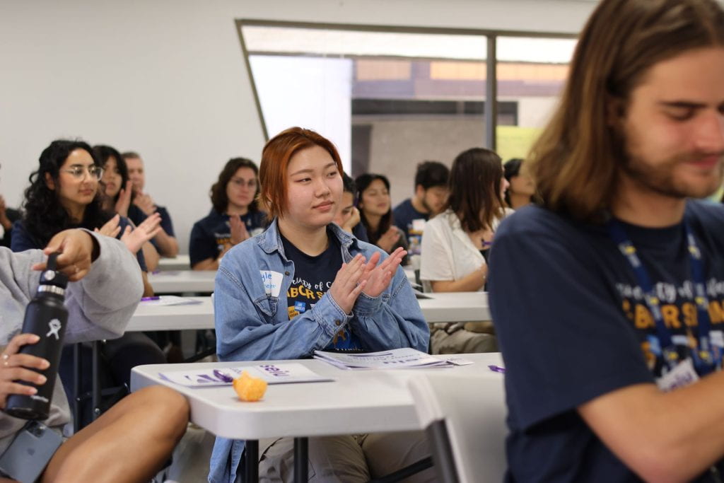 student in focus clapping in lecture setting