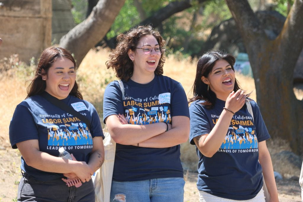 three students side by side laughing in labor summer shirt