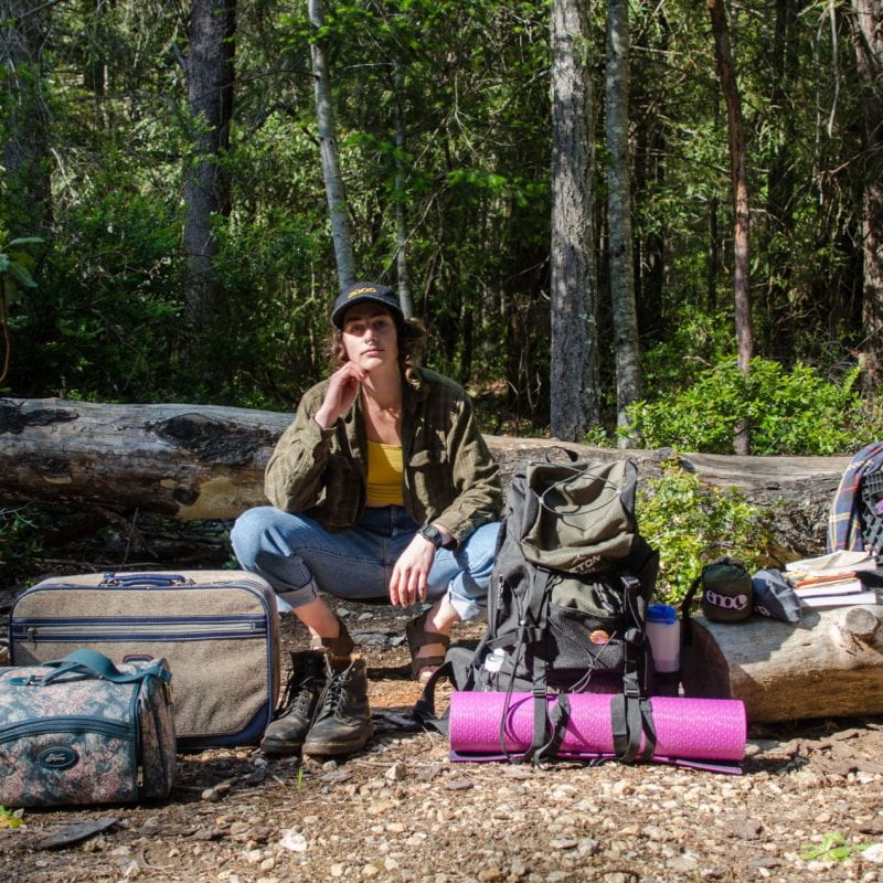 student with belongings in the woods