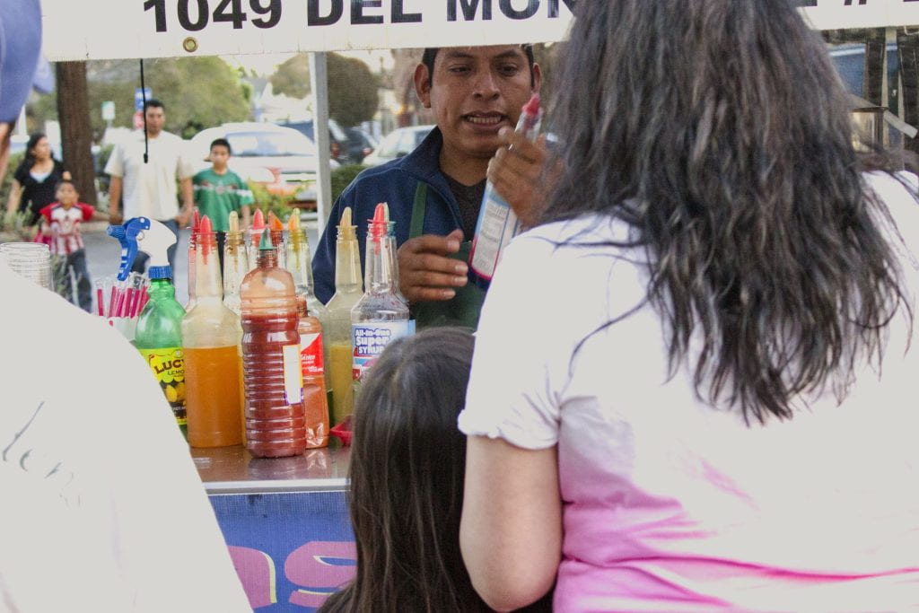 three people in line at a festival stand with a worker behind the counter