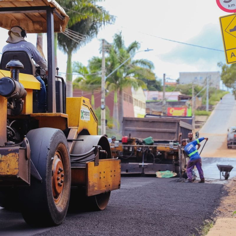 a man driving a construction vehicle down a street in Ribeirão das Neves, Brasil by Hector Brasil 